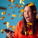 Celebrating,Young,Woman,With,Mobile,Phone,Winning,Prize,And,Showered