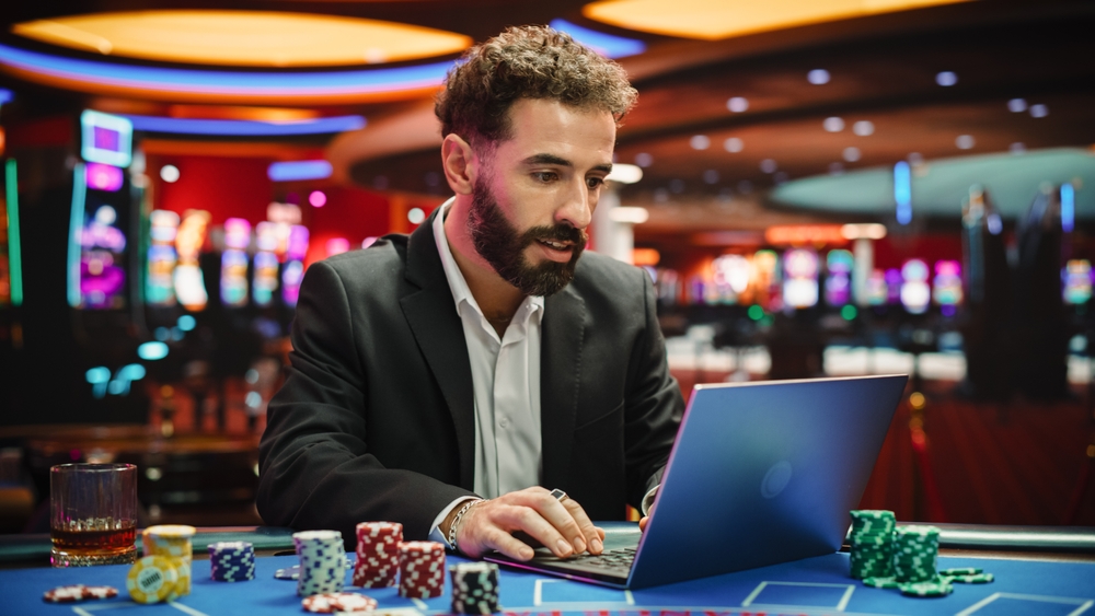 Portrait,Of,A,Young,Man,On,Casino,Floor,,Using,Laptop